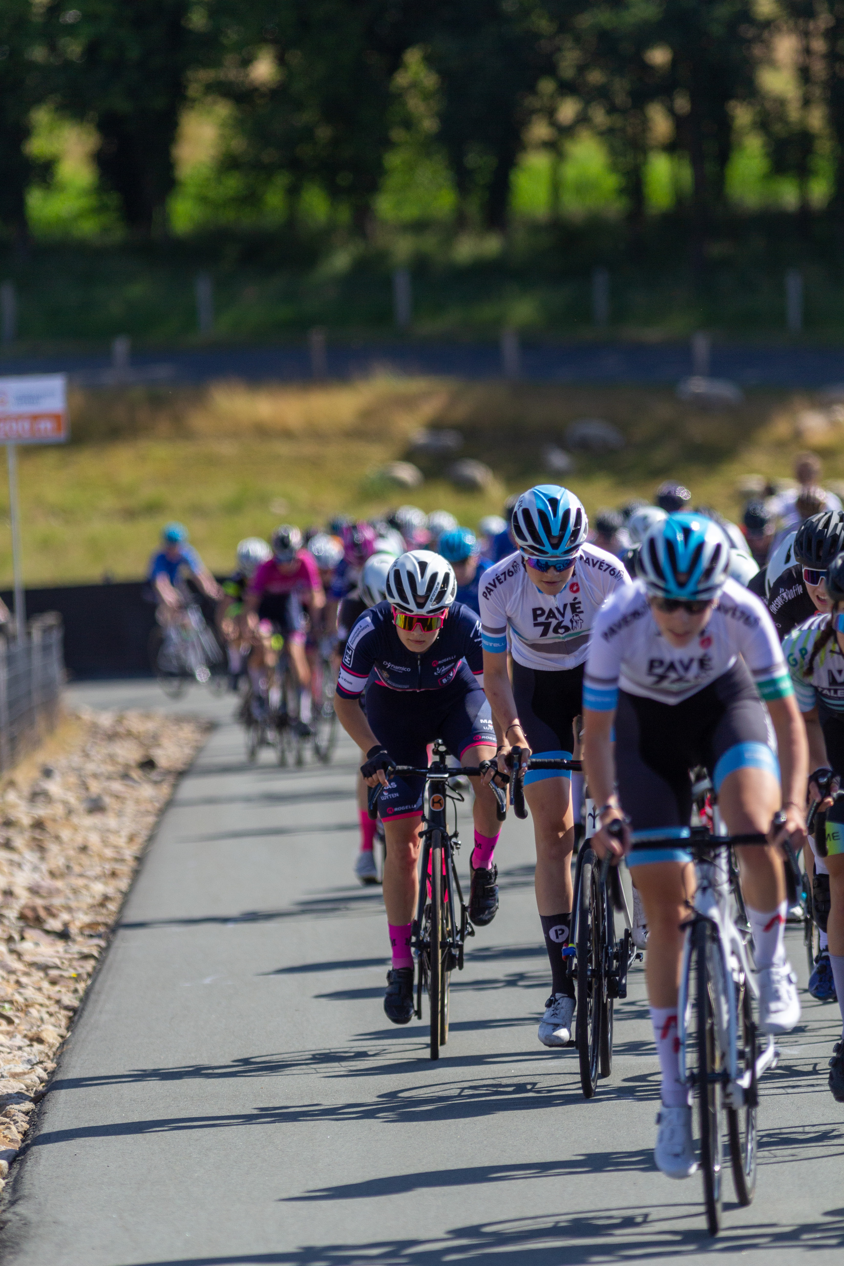 A group of bicycle racers are participating in a race through a park.