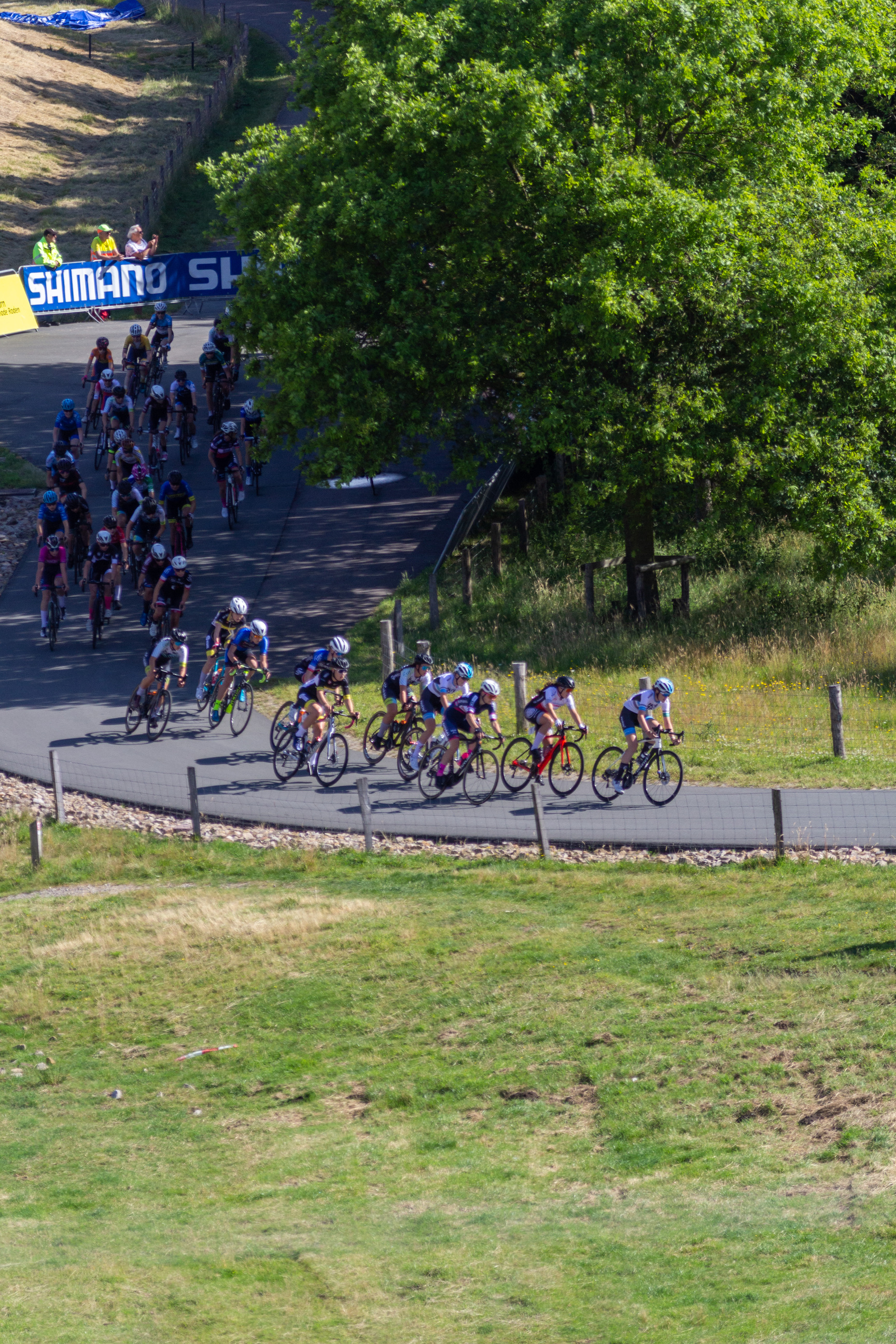 A group of cyclists race down a hill in a Wielrennen event.