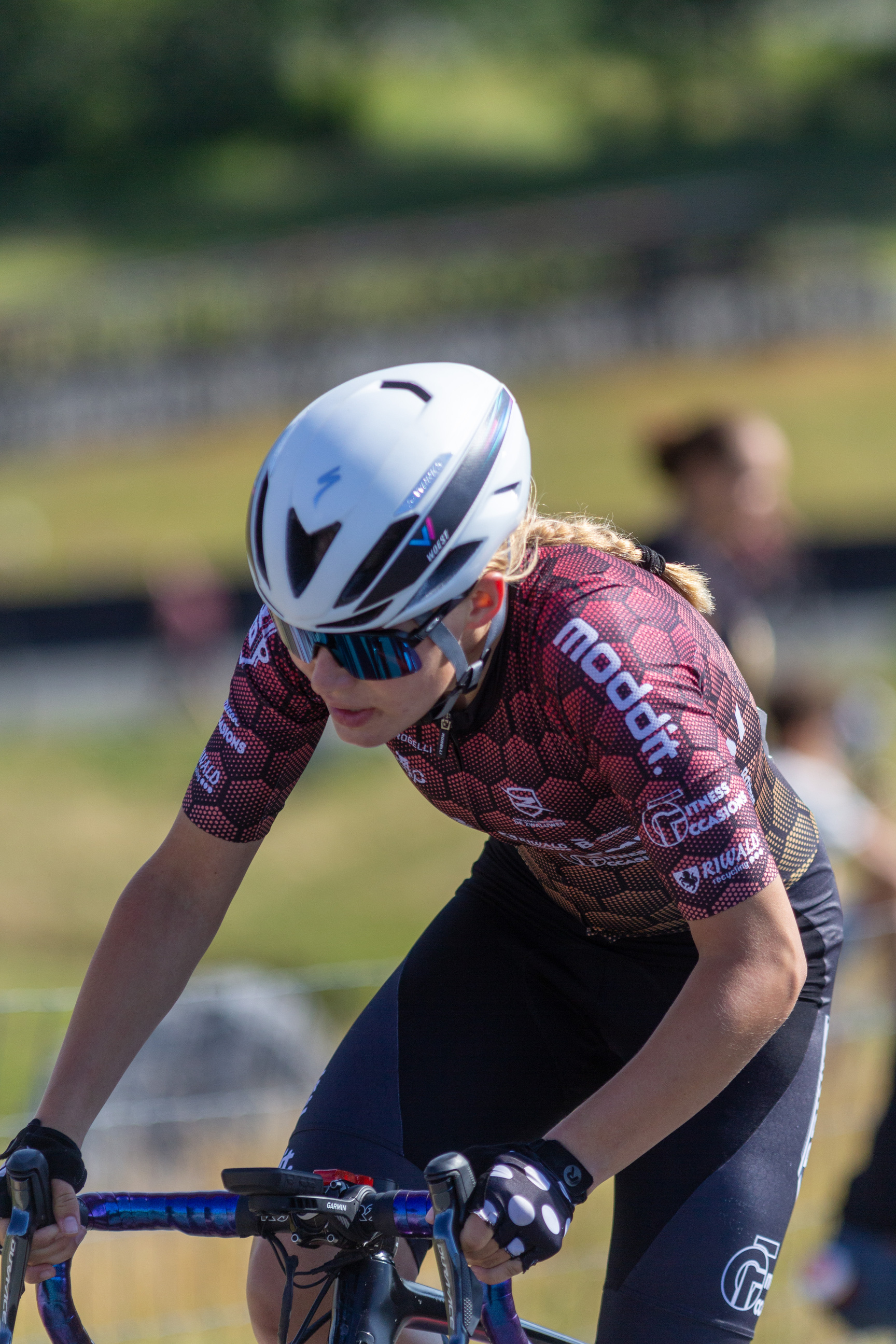 A cyclist in a red and black shirt races on a track.