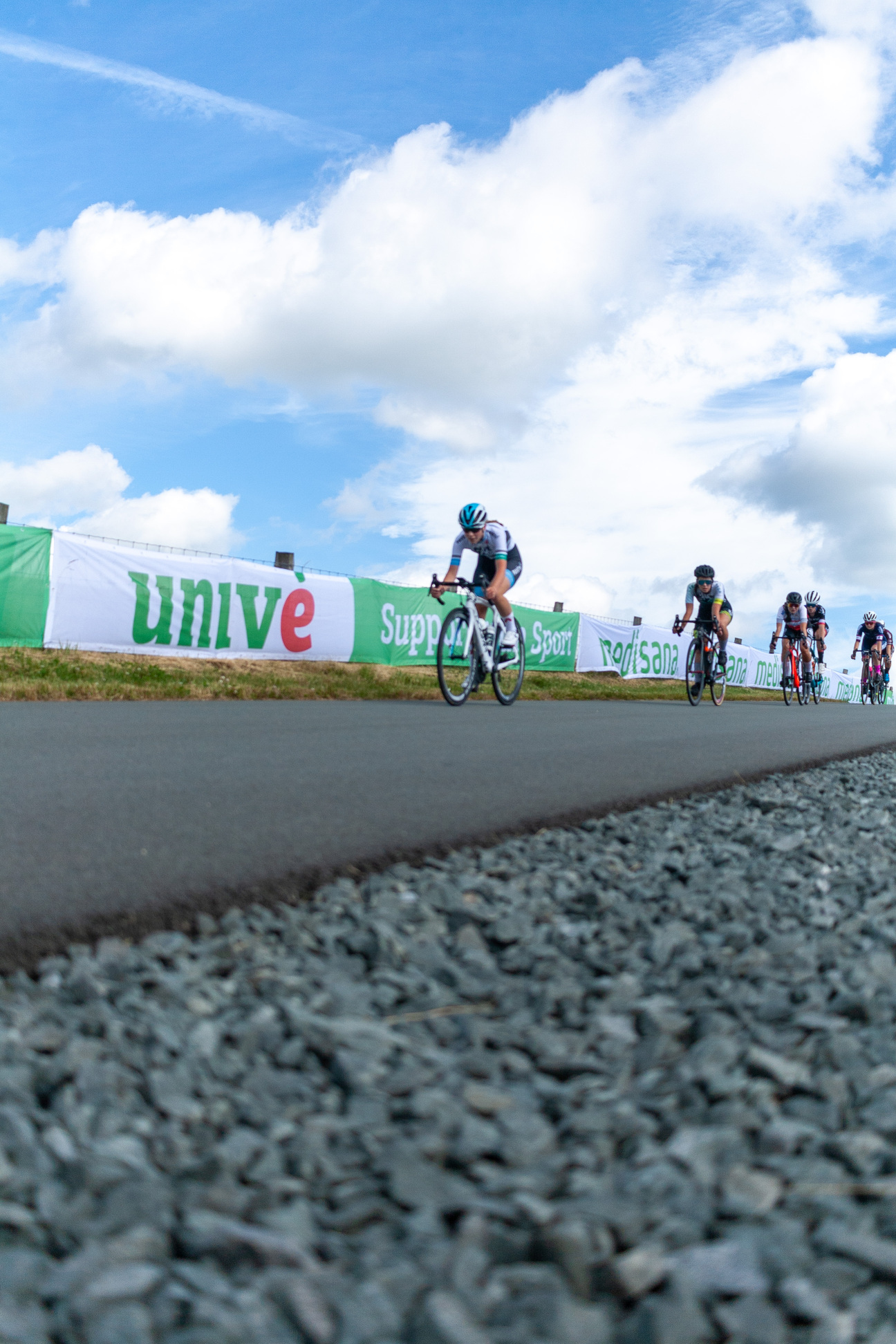 A cyclist is riding a bike down the road as other cyclists are behind her.