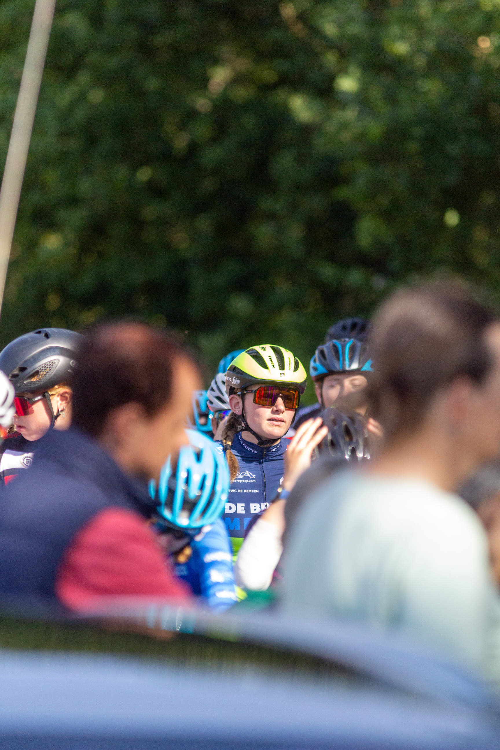 A group of cyclists wearing blue and pink outfits with their helmets on.