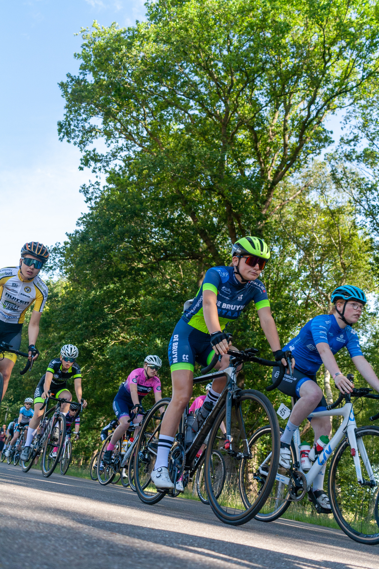 A group of cyclists, one with the word "Bicycle" on their shirt, ride through a forested area.