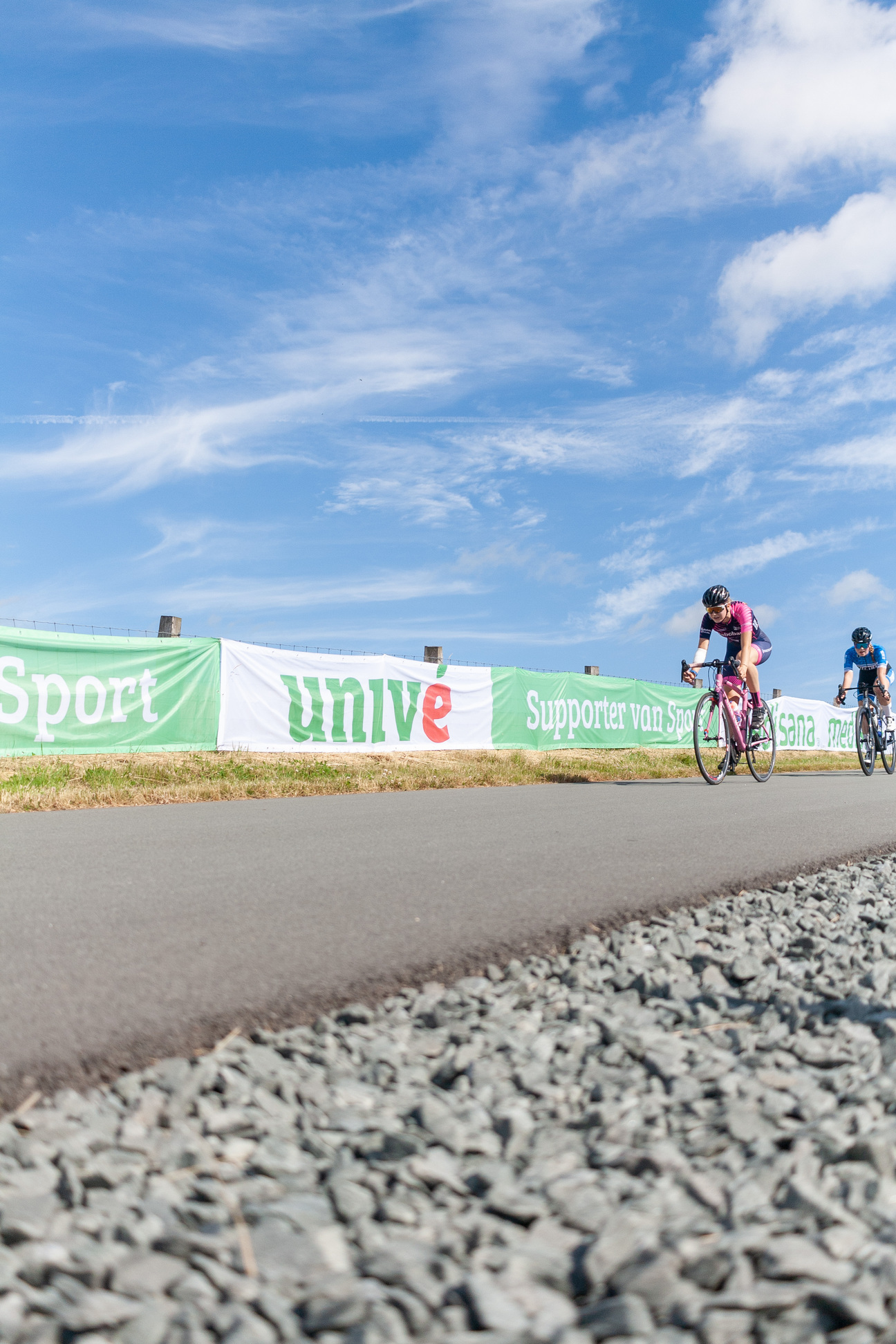 Two female cyclists compete in a race on a sunny day.