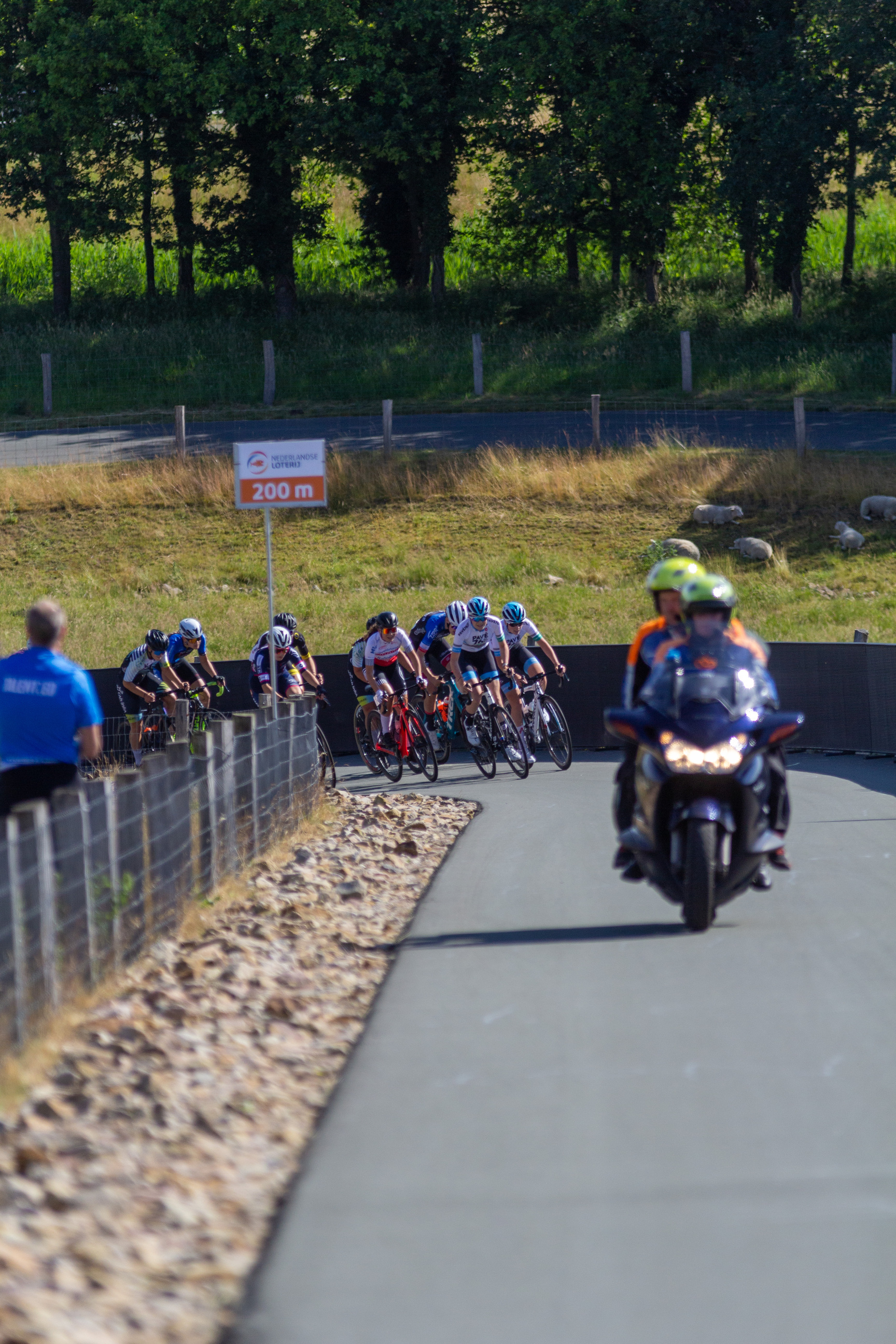 A cyclist competition on a track with people watching from the side.