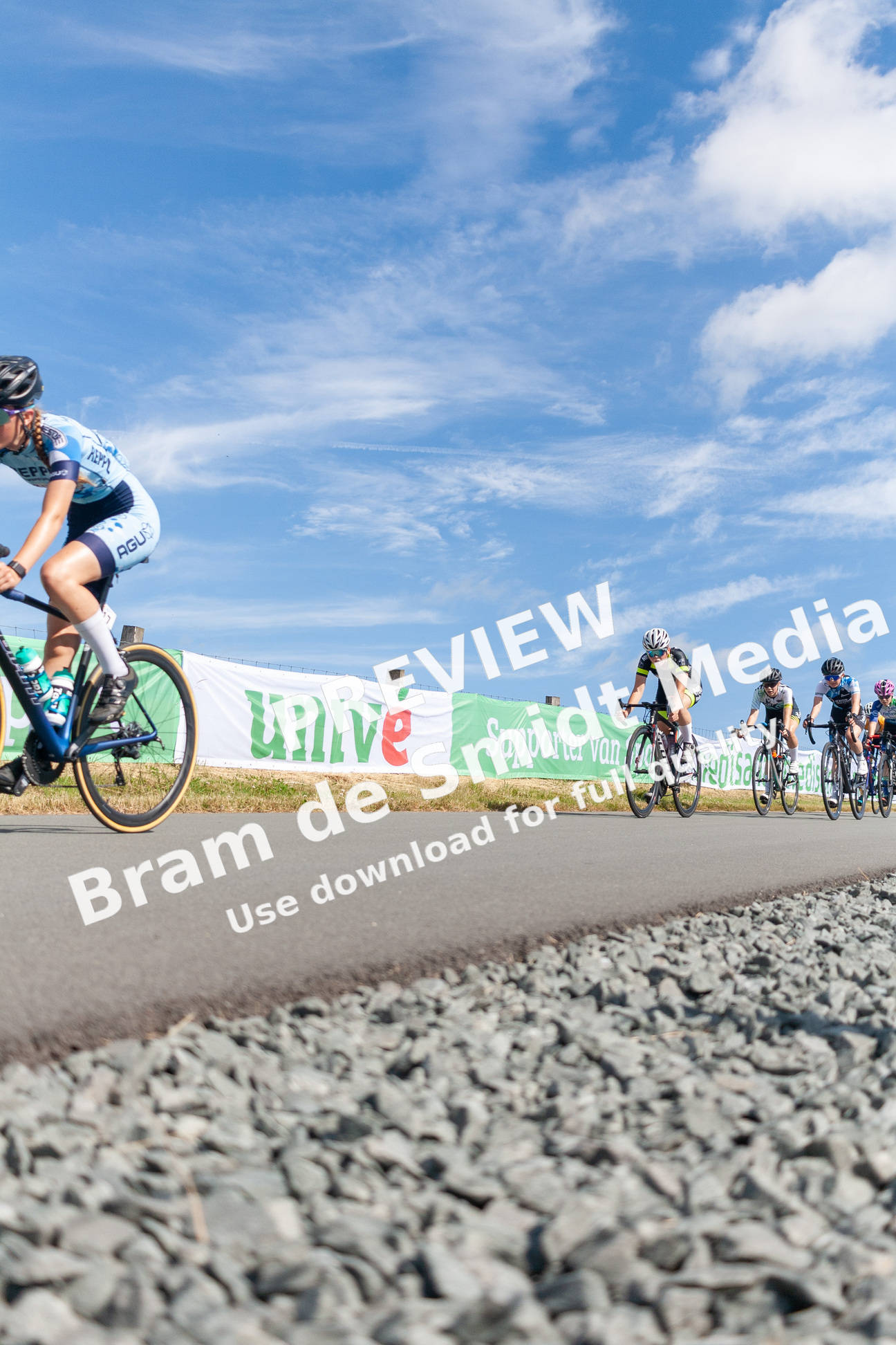 A group of bikers riding down a road near a sign that says "UNICEF" on it.