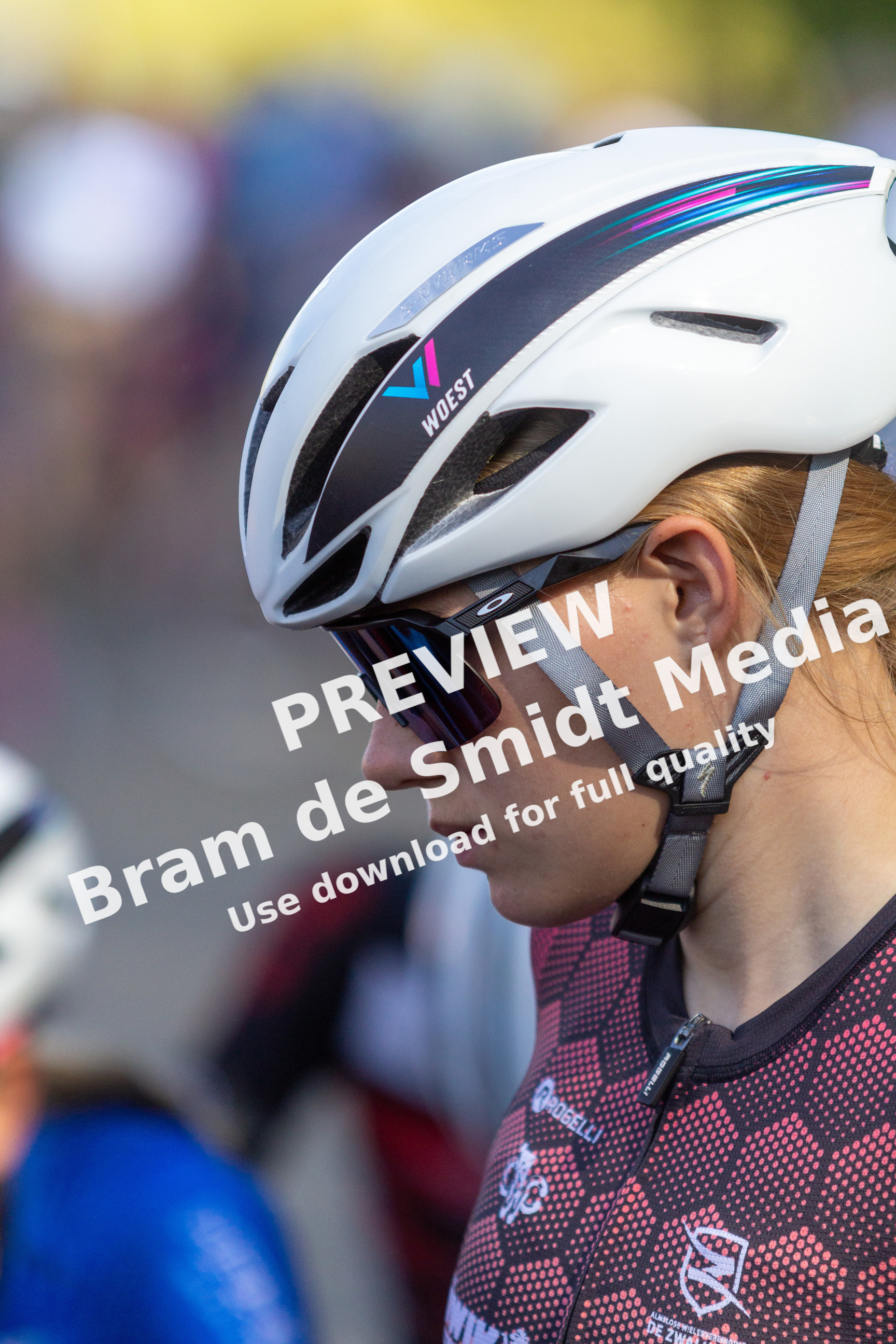 Woman wearing a helmet and sunglasses walking in a field with other people.