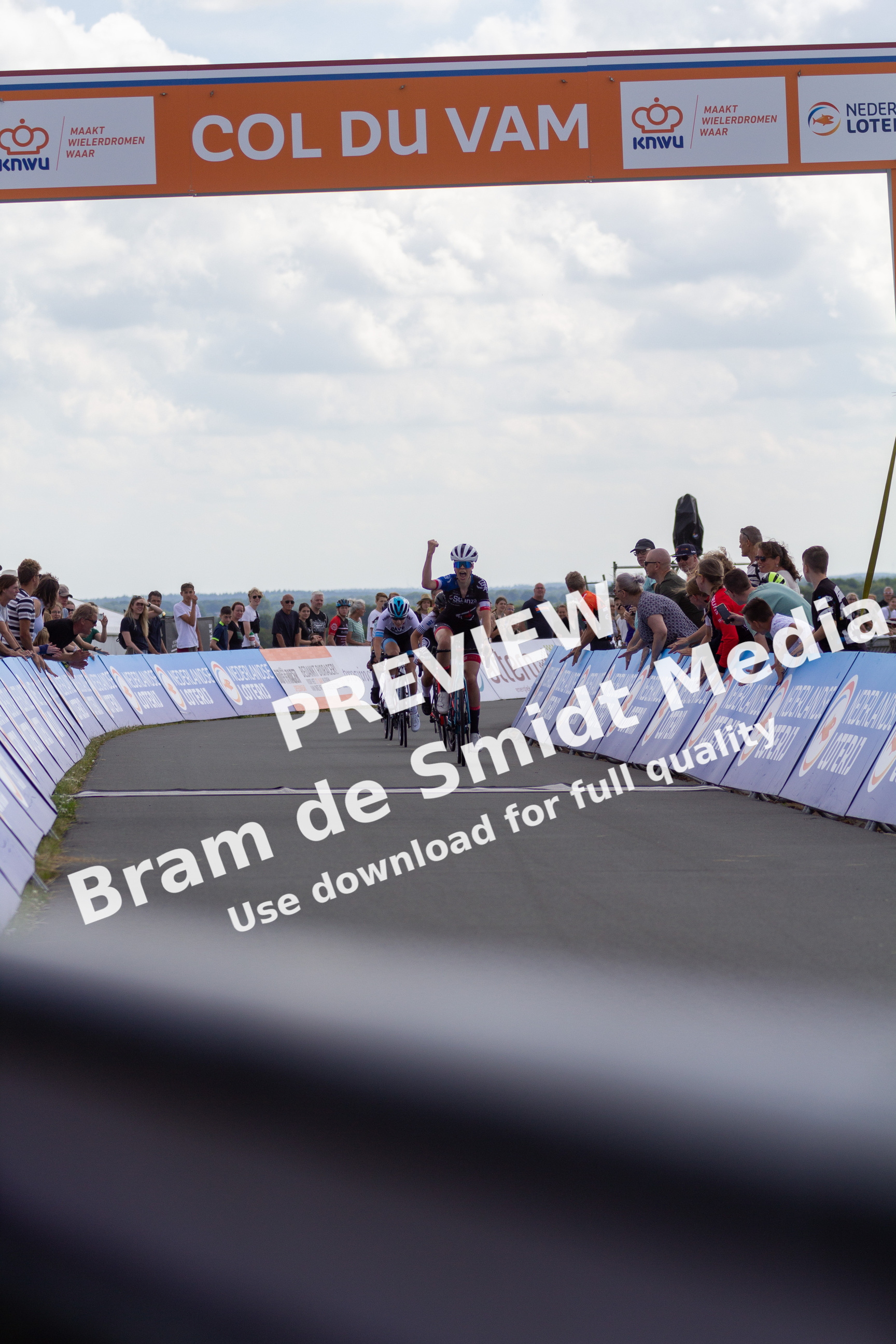 A group of people are gathered to watch a man ride his bike down a track.