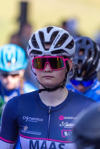 A girl in a blue and pink outfit is riding her bike in a bicycle race.