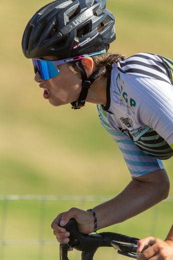 A woman is wearing a white and blue jersey with the word "Wielrennen" on it as she rides her bike.