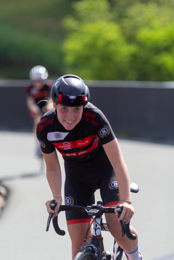 A lady wearing a helmet and a bike with the word NK Dames on it.