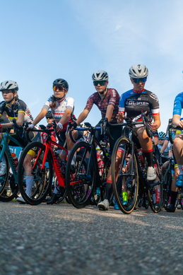 A group of cyclists wearing helmets and biking gear stand together in a row.