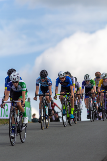 A group of cyclists on a road with 2022 Wielrennen signs on the side.