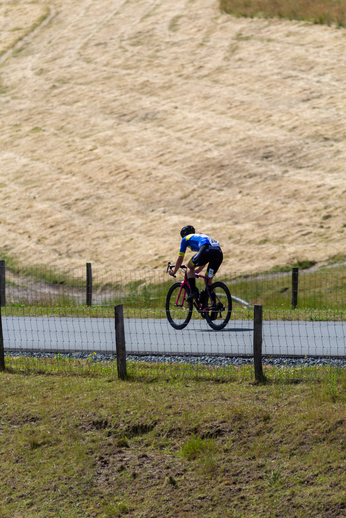 A biker in a blue shirt rides her bike on the street.