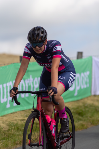 A woman in a blue jersey riding a bicycle on the road.