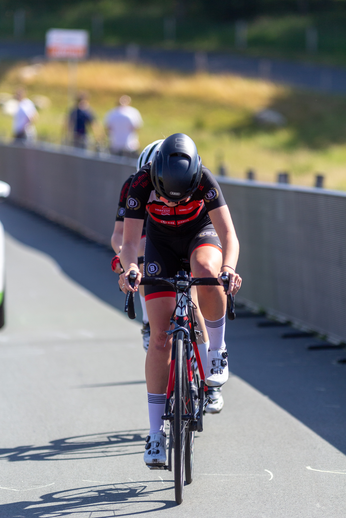 A woman wearing a black and red shirt riding her bike on the road.