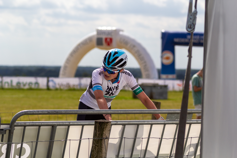 A biker wearing the number 5 jersey on a track near a tunnel.