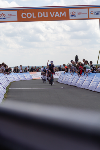 A group of people are gathered to watch a man ride his bike down a track.