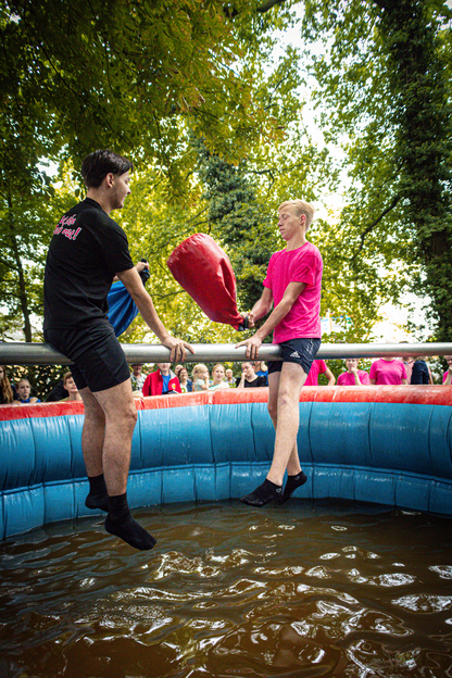 Two people standing on a rubber mat, one holding a heart and the other holding balloons.