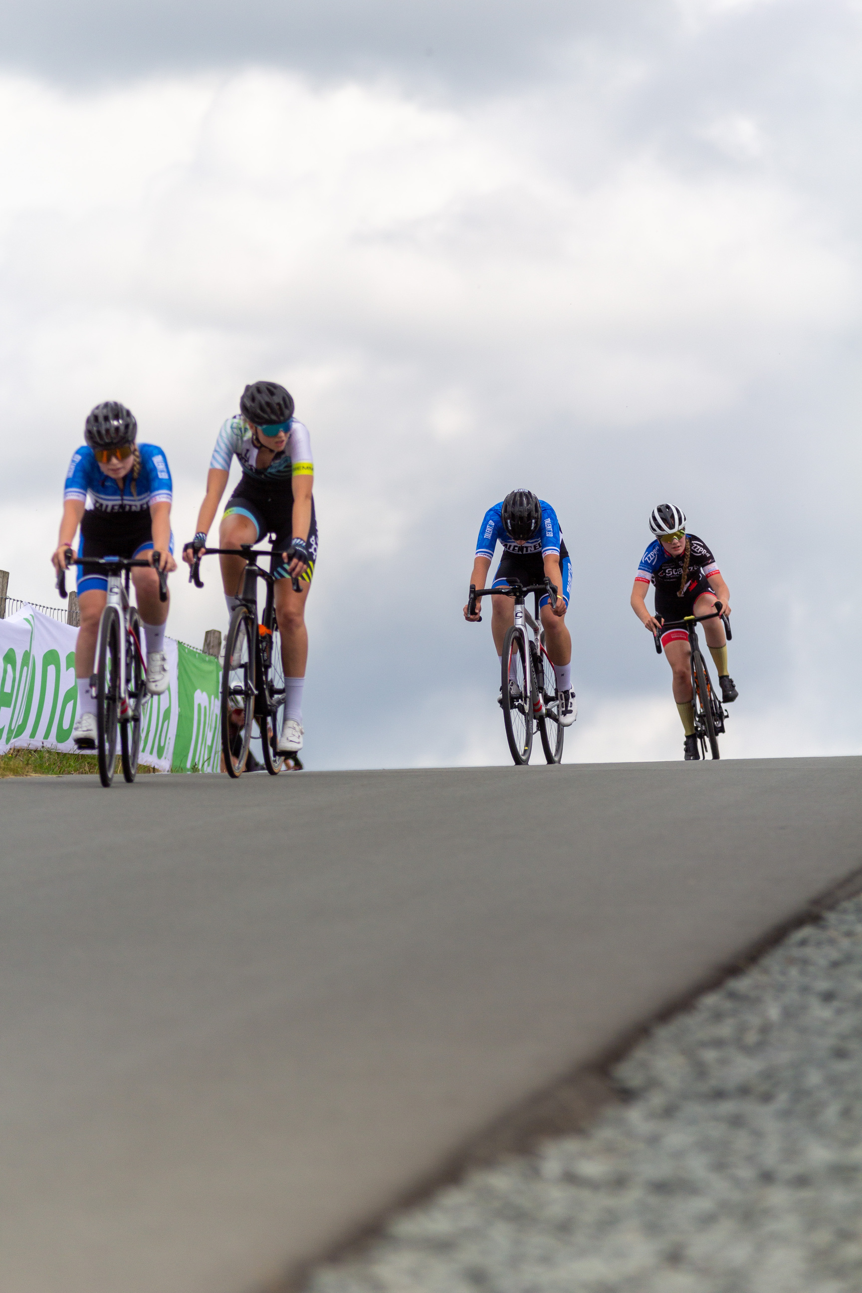 Three cyclists are on a road in an area for Juniors.