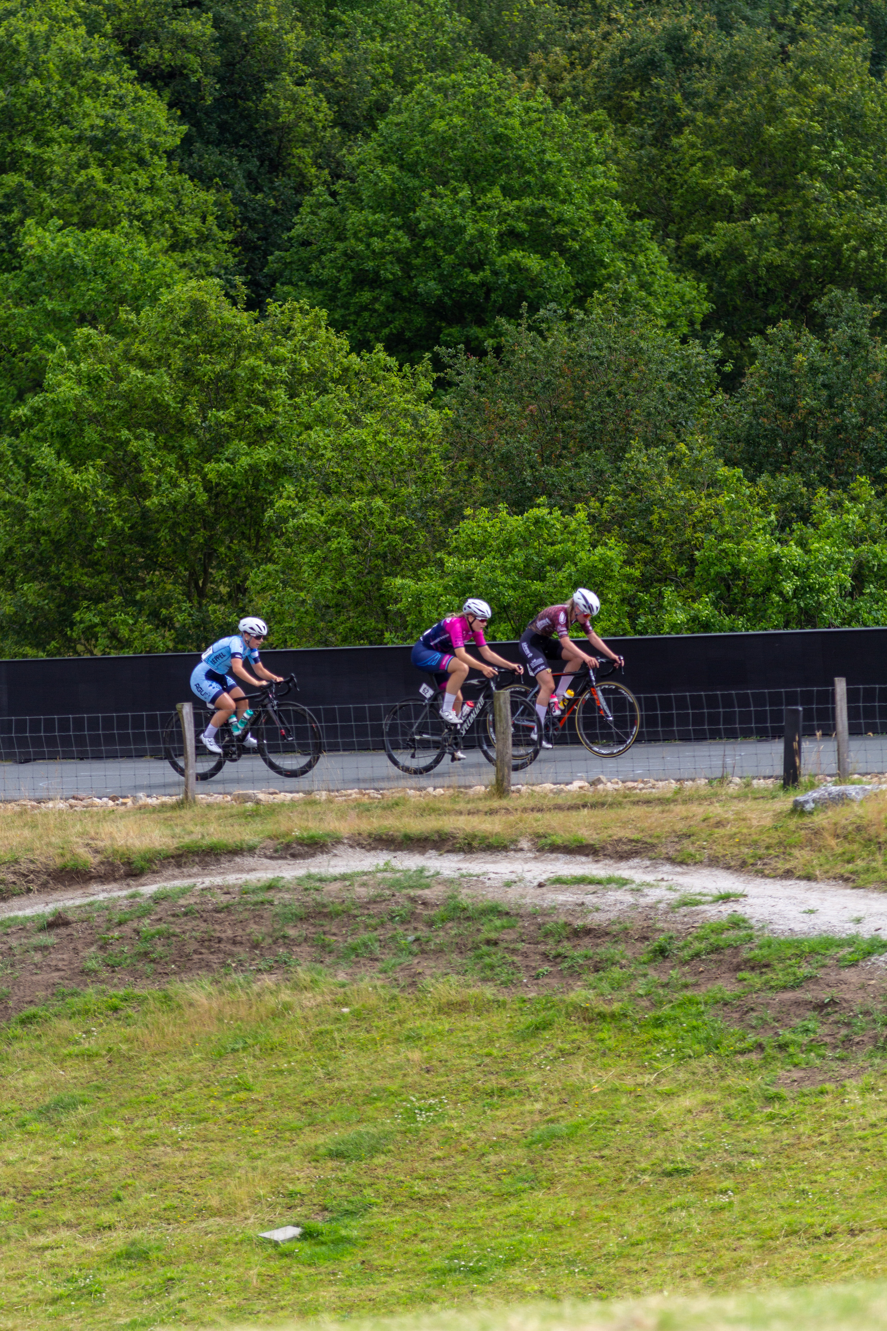 Three cyclists racing on a road with one rider wearing the number 21.