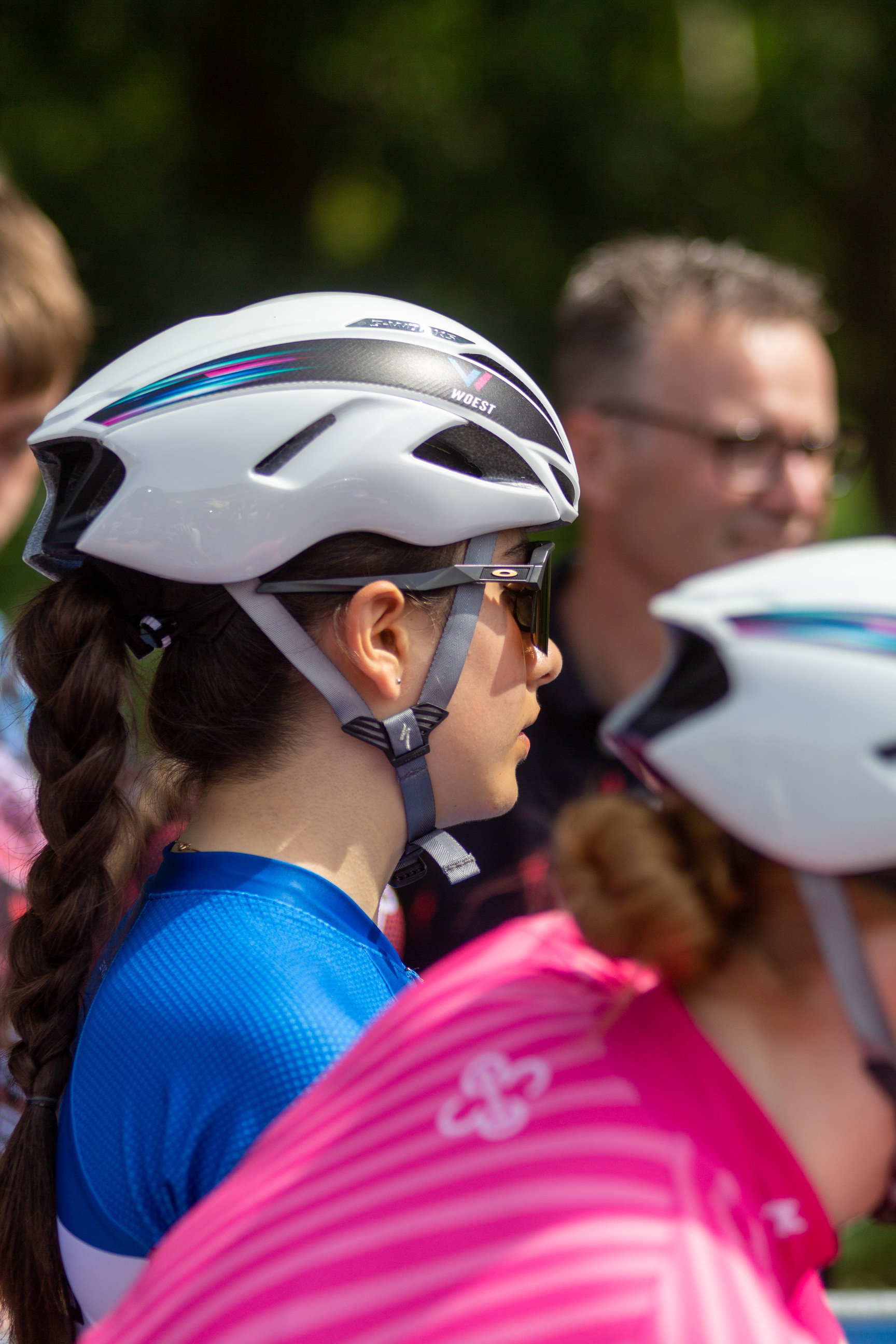 Pink shirt next to a person with blue shirt and a white bike helmet.