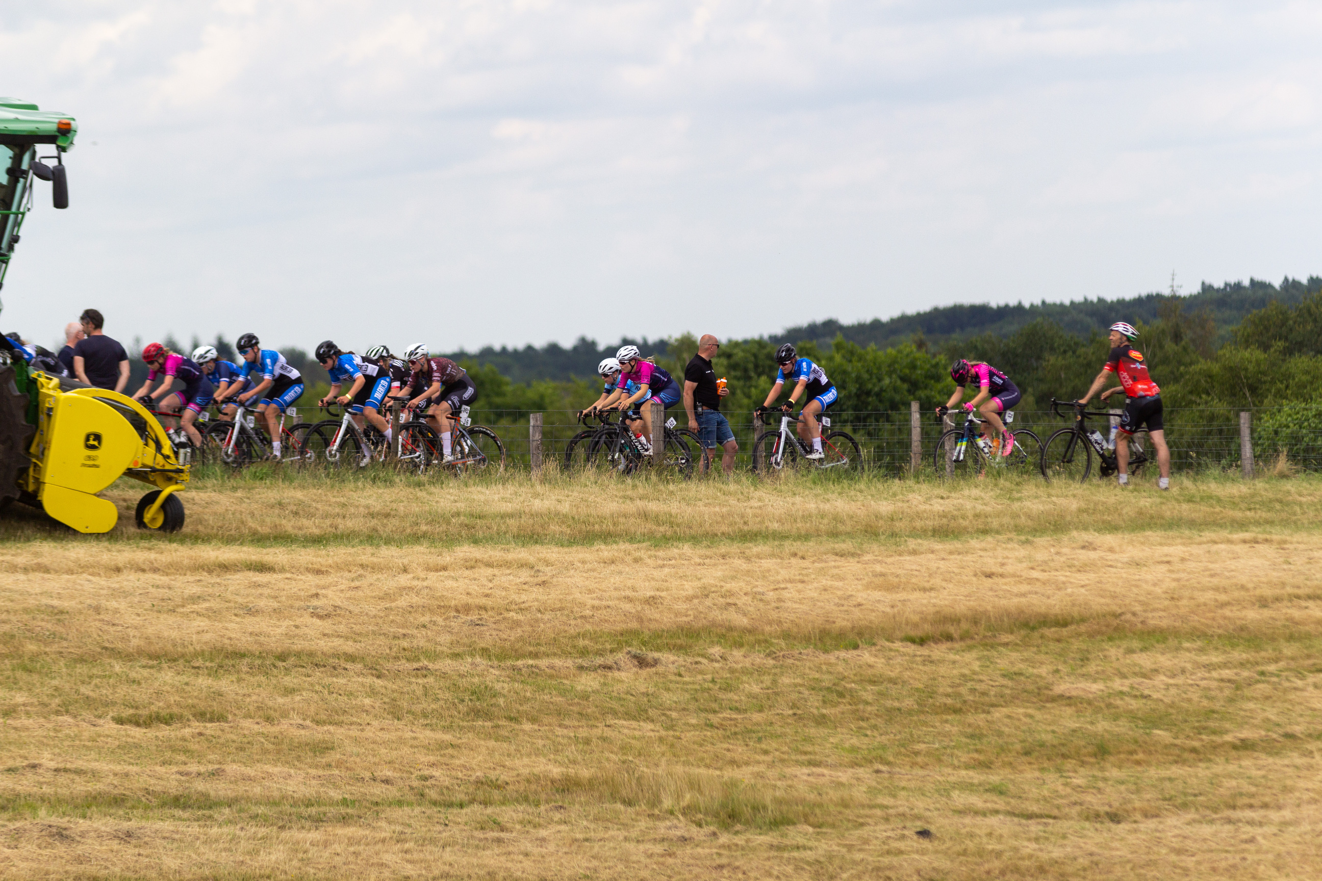 Wielrennen Junior Dames event taking place on a sunny day with people riding bikes on a grassy field.