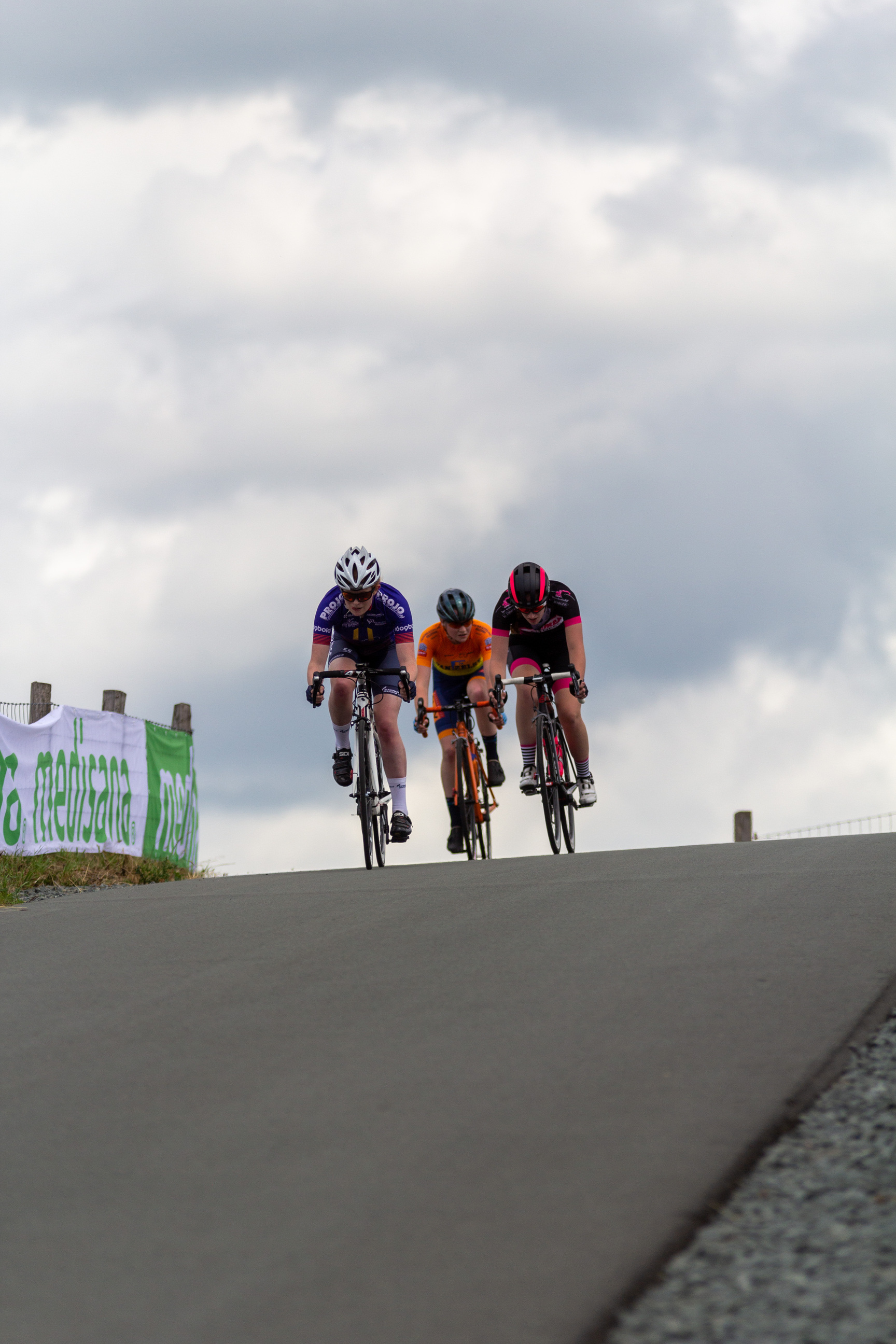 Three people are riding bikes on the road together.