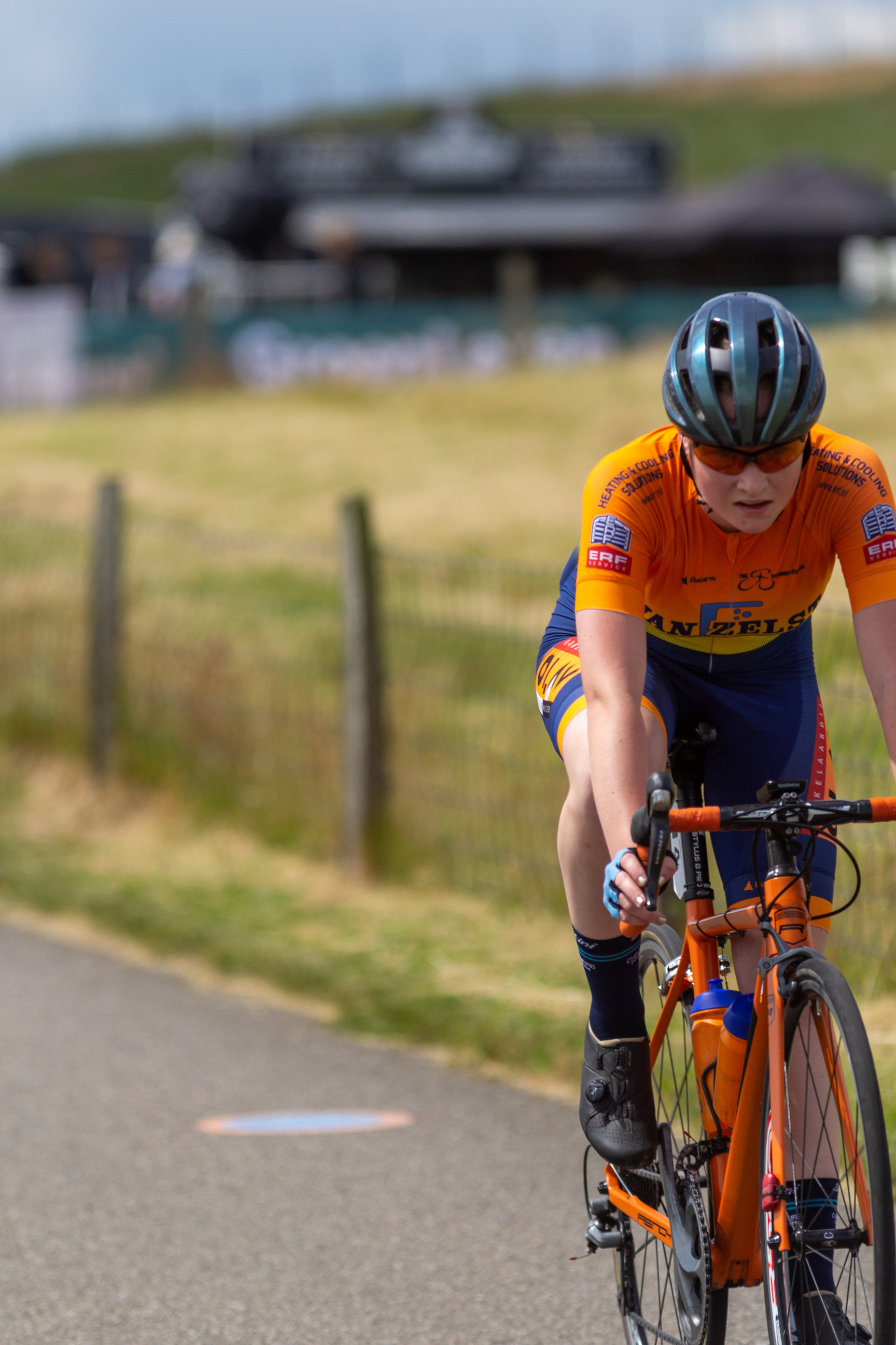 A woman wearing a blue helmet riding an orange bike with the word "Giant" written on it.