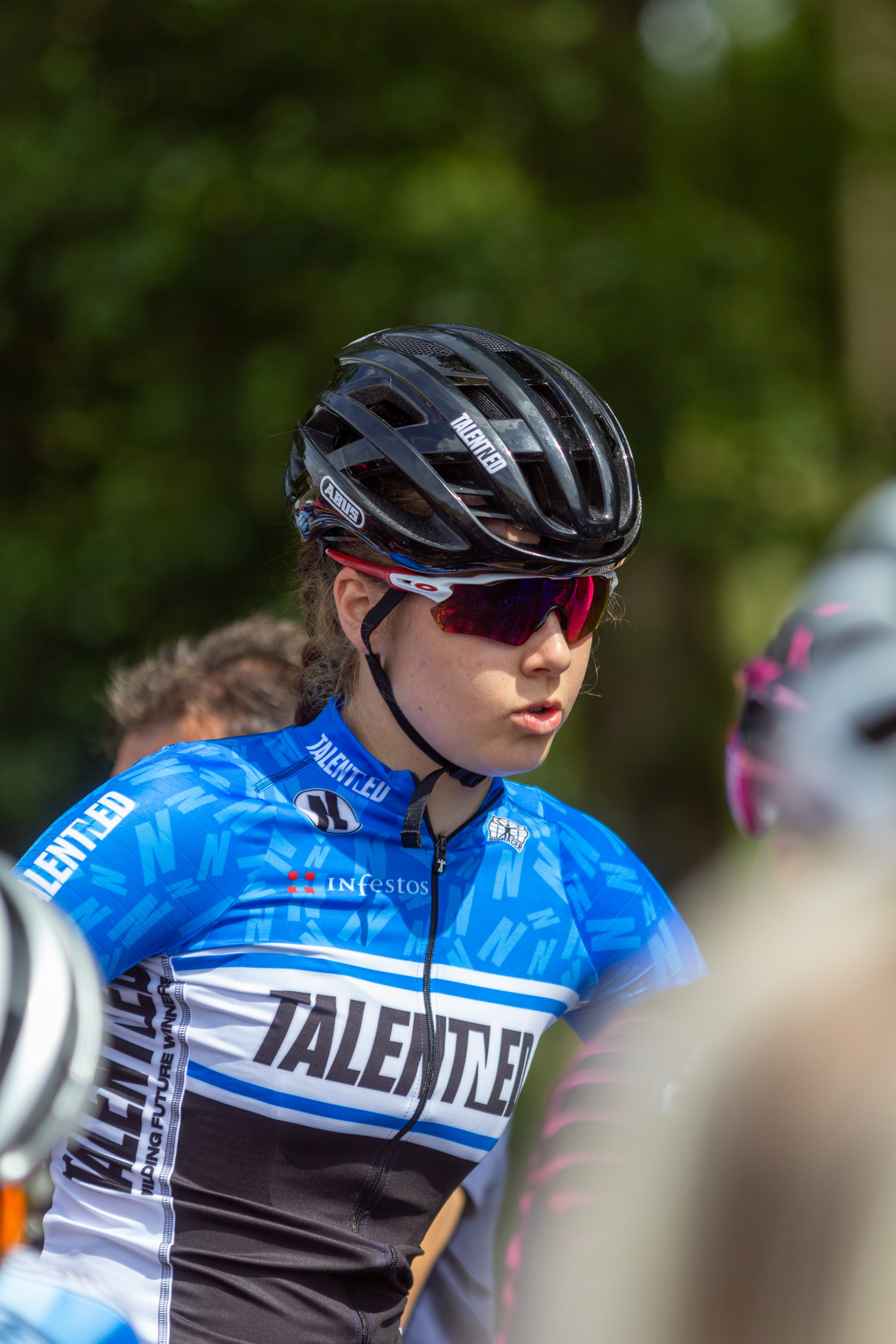 A woman wearing a blue shirt is riding her bike in the race.