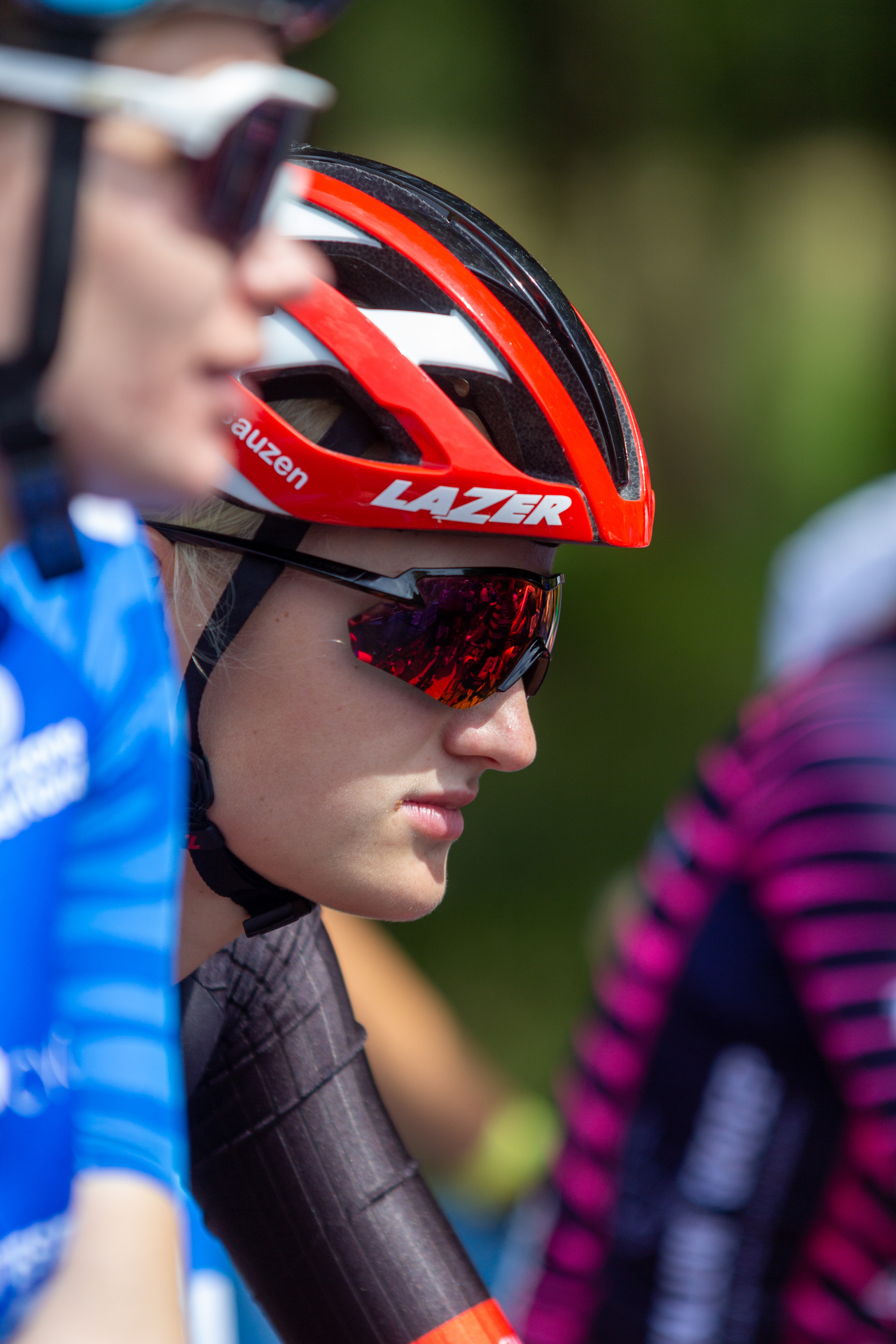 A cyclist wearing a black jersey with red stripes and an orange bike helmet.