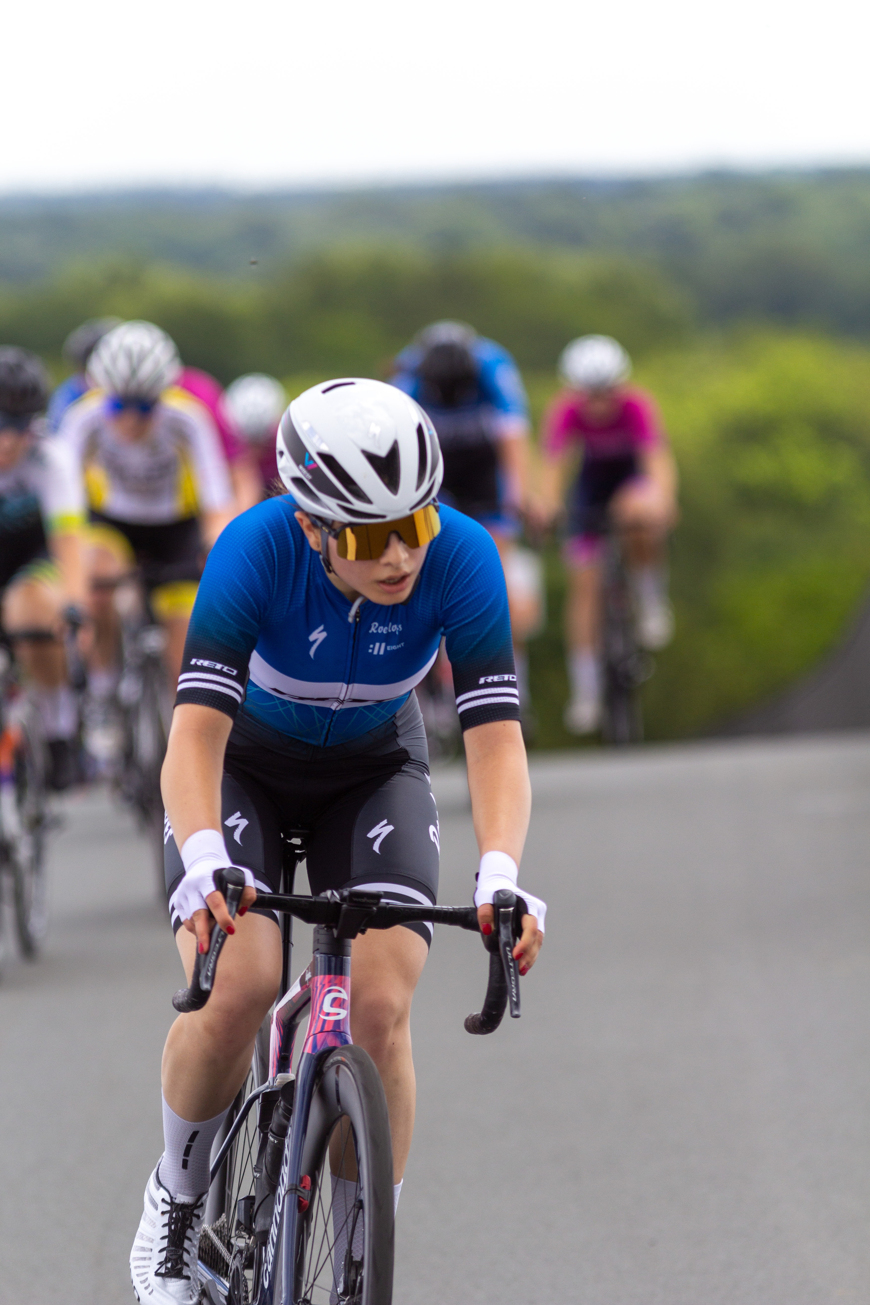 A woman in a blue shirt is riding a bike down the street.