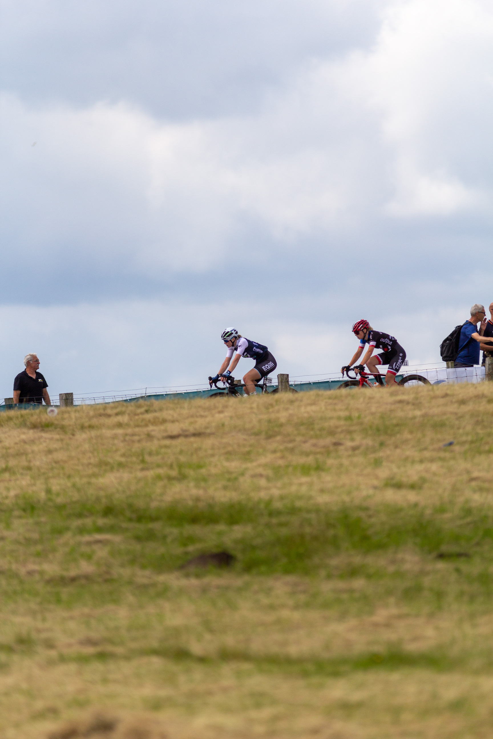 Junioren Dames 2022 is about the women cycling race, in which two cyclists are riding on a hill with other people watching.