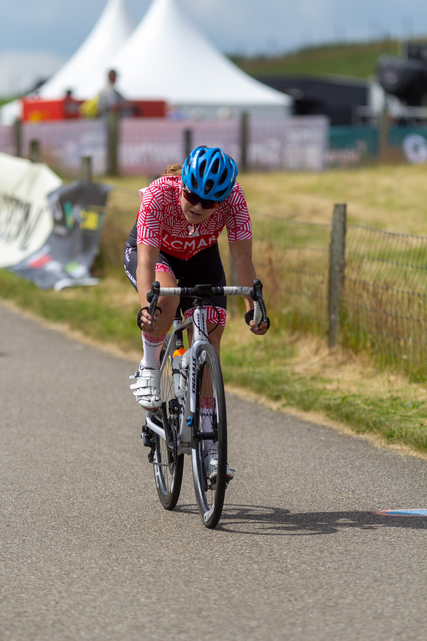 A woman in a red and white striped shirt is riding a bicycle, likely participating in a cycling event.