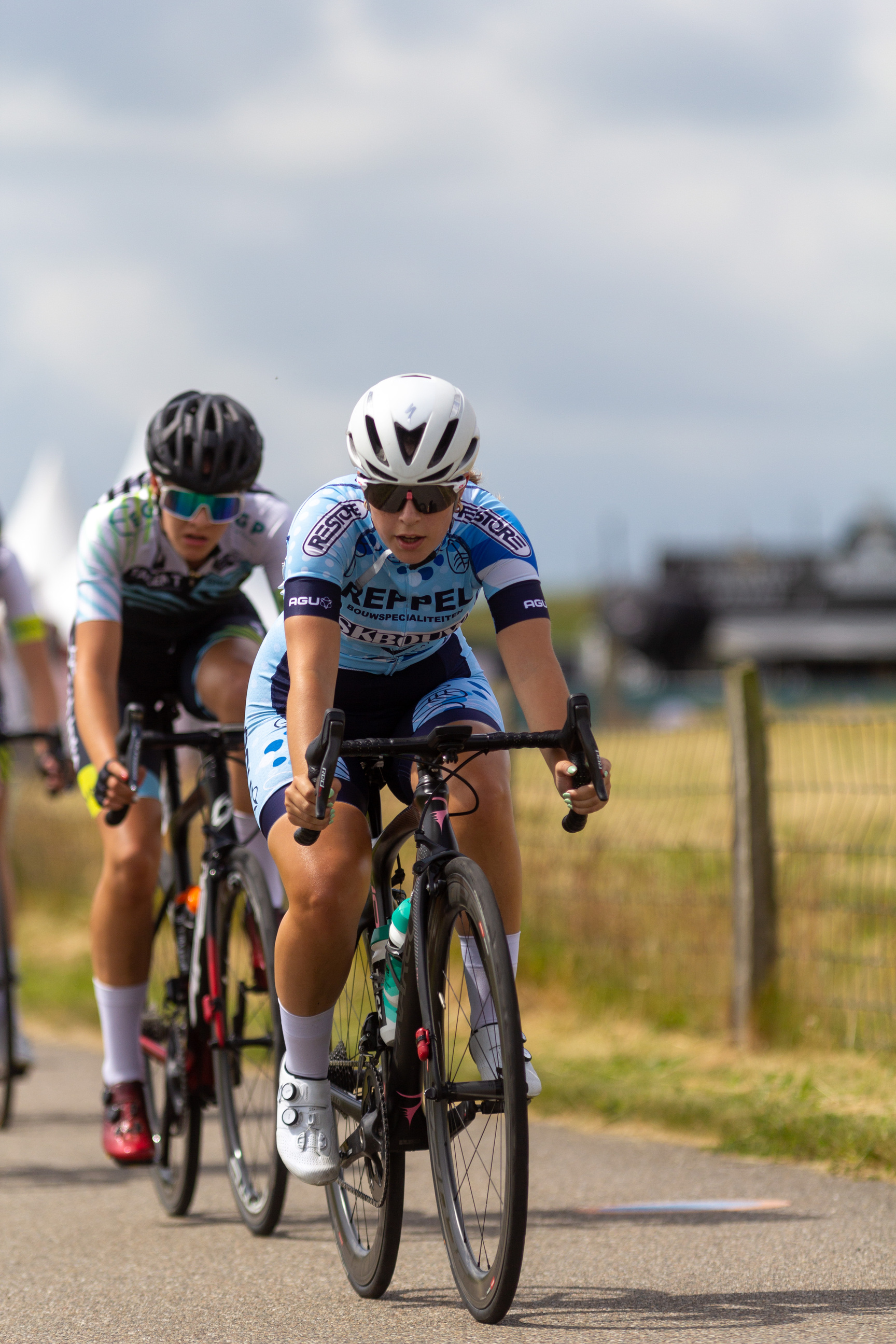 Two young female cyclists on a street with one wearing a shirt reading KPEPP.