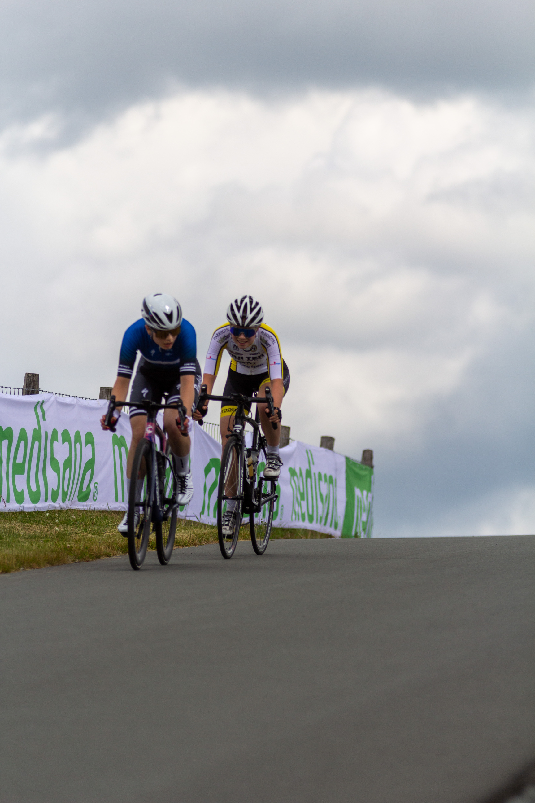 Two cyclists are racing on a track with the word "mediaset" in green above them.