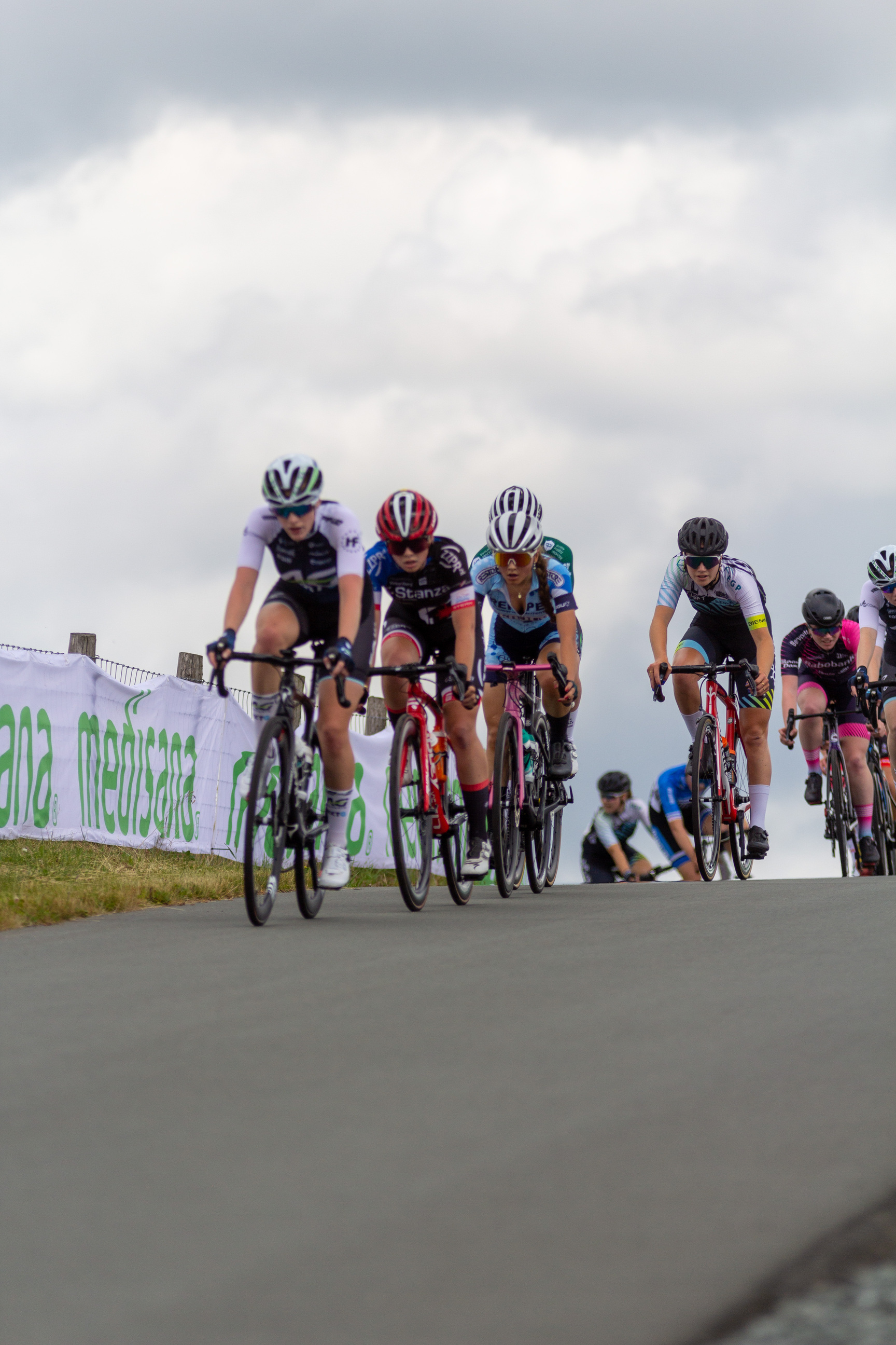 A group of cyclists race on a road, including one wearing a pink jersey.