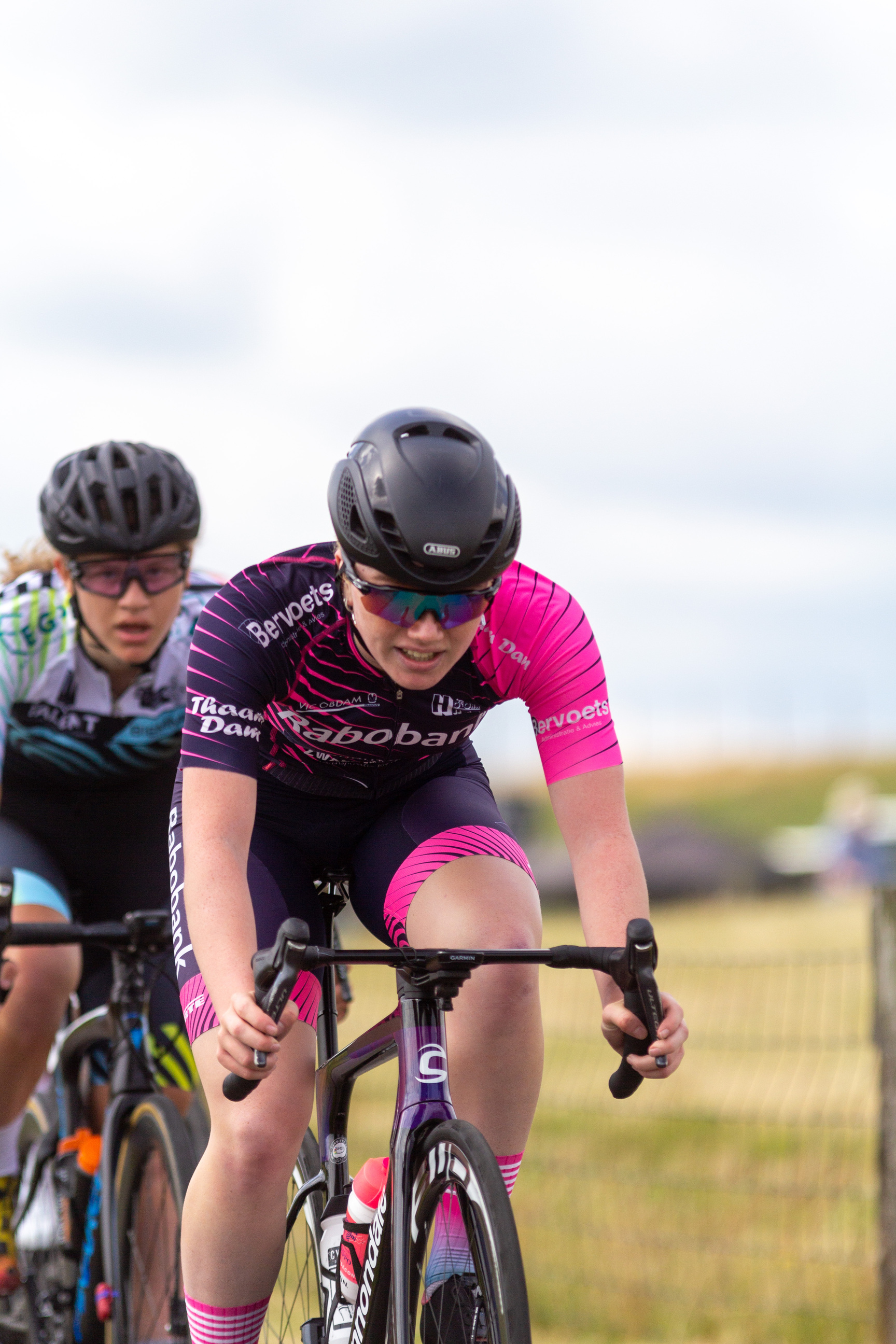 Two women are racing on their bikes in a race sponsored by NK Dames.