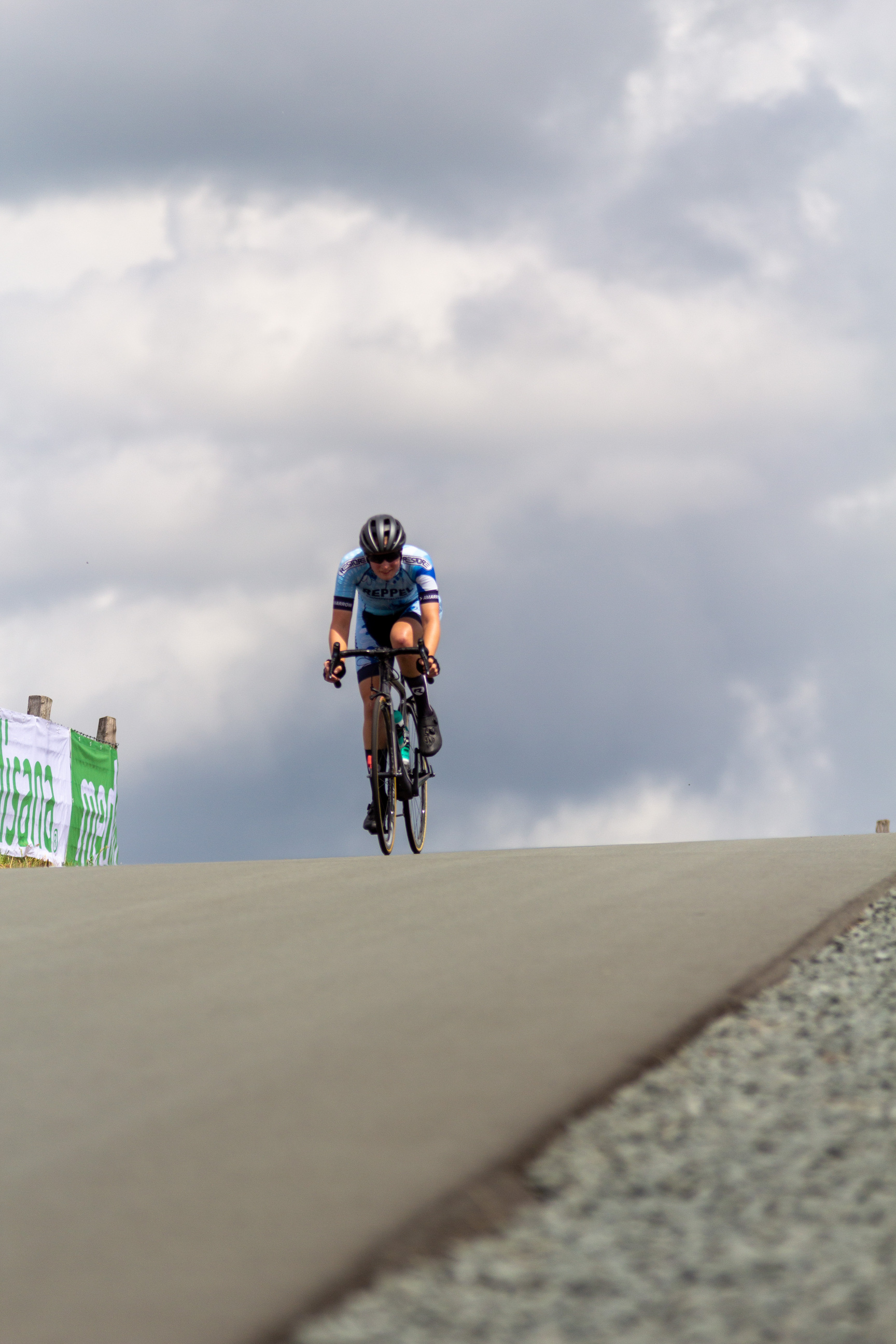 A cyclist wearing a blue jersey is riding on a hill.