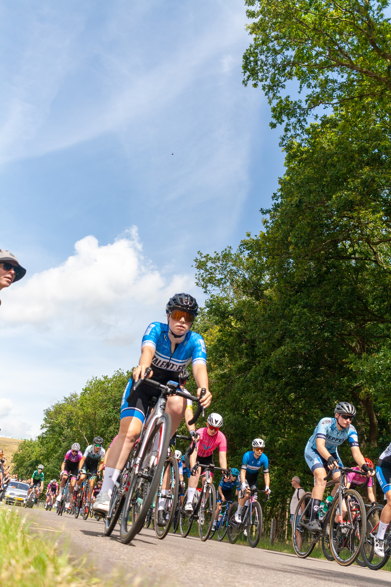 A group of cyclists race down a road, with the winner being number 10.