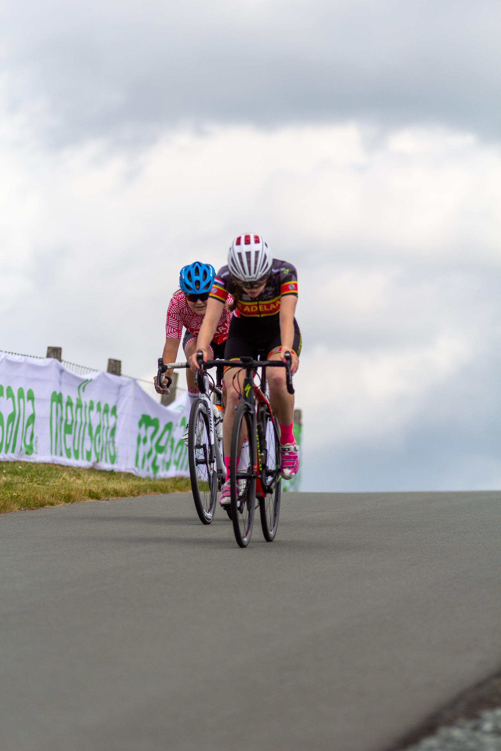 Two cyclists, both wearing safety helmets, are racing.