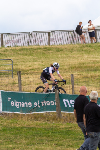 A man on a bicycle at a race sponsored by NK Dames and Wielrennen.