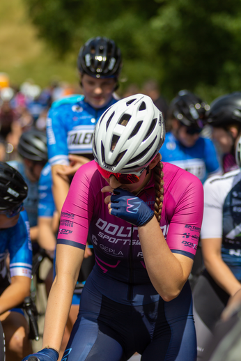 A photo of a group of cyclists with Wielrennen and NK Dames in the background.