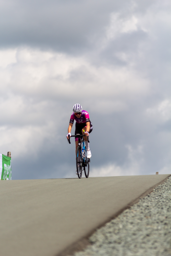 A person wearing a pink jersey rides a bicycle down a steep hill.