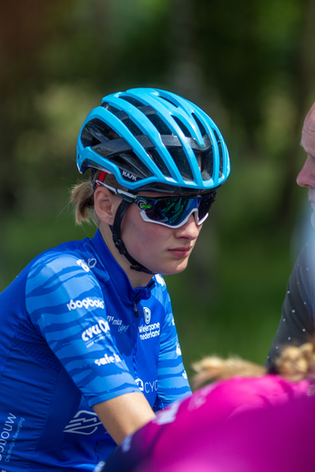 A woman in a blue jersey with the number 2022 and a blue helmet wearing sunglasses on top of her head.