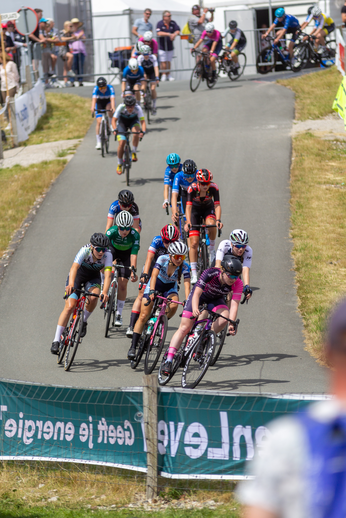 Junioren Dames 2022 banner on fence behind a cyclist.