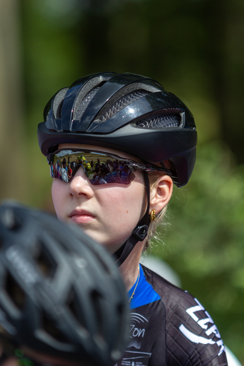 A young woman is wearing a helmet and sunglasses while riding her bike.