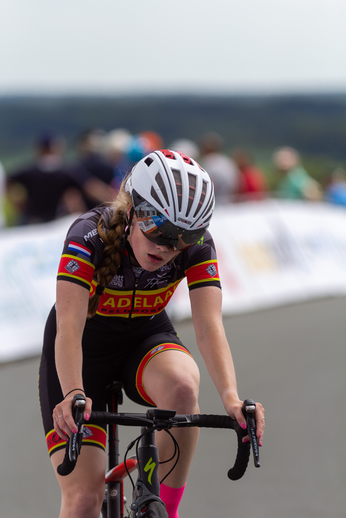 A cyclist is wearing a red and black shirt with Adela written on it.