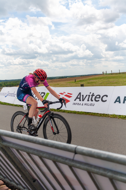 A woman riding a bike down the road with the word Avitec in the background.