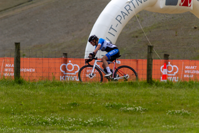 A man is wearing a blue and black outfit while riding his bike.