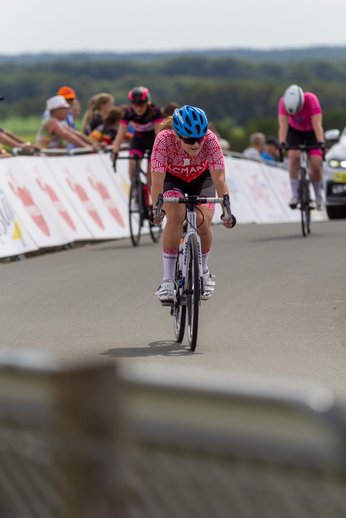 A woman is riding a bicycle wearing a pink and red outfit with 3 other people.